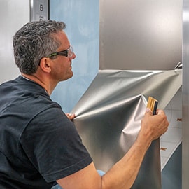 Man installing silver metallic 3M DINOC finish to elevator door