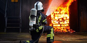 firefighter climbing a ladder of a burning house
