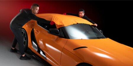 orange car wrap being installed by two installers
